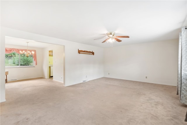 carpeted empty room featuring ceiling fan with notable chandelier