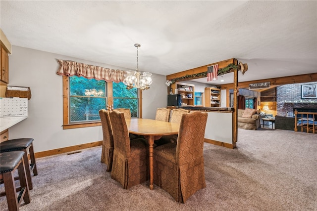 carpeted dining space with a brick fireplace, a notable chandelier, and a textured ceiling