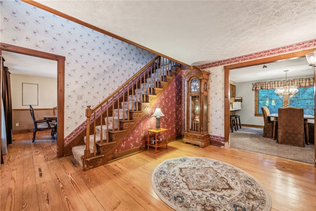 foyer featuring wood-type flooring, ornamental molding, a textured ceiling, and an inviting chandelier