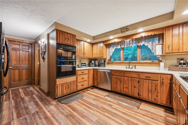 kitchen featuring light hardwood / wood-style flooring, sink, black double oven, and stainless steel dishwasher