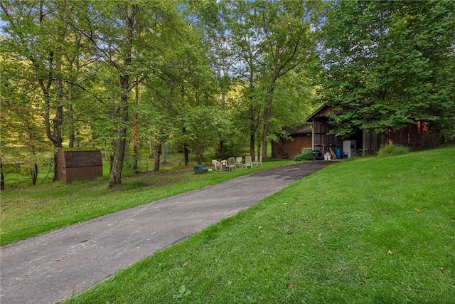 view of property hidden behind natural elements with an outdoor structure and a front lawn