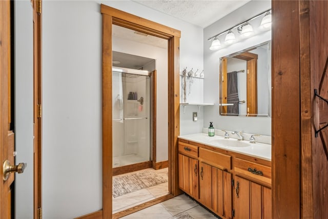 bathroom featuring a textured ceiling, vanity, and an enclosed shower