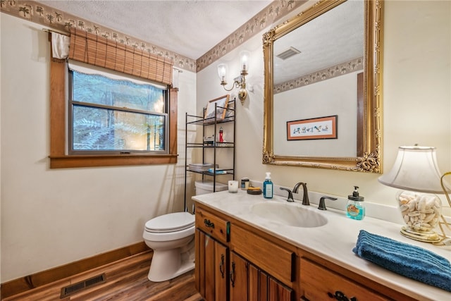 bathroom with a textured ceiling, hardwood / wood-style floors, vanity, and toilet