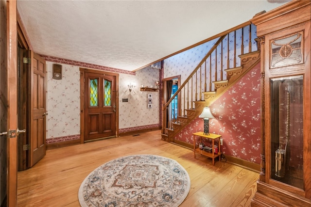 entryway featuring wood-type flooring, a textured ceiling, and crown molding