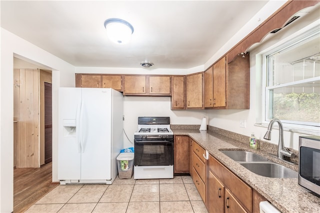 kitchen with light wood-type flooring, white appliances, and sink