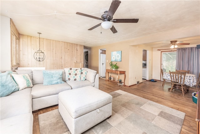 living room featuring ceiling fan, wooden walls, and wood-type flooring