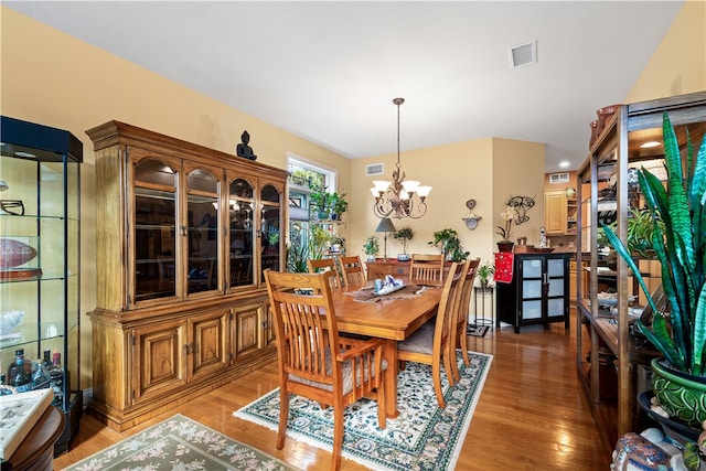 dining space with hardwood / wood-style flooring and a notable chandelier