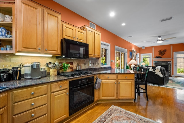 kitchen featuring ceiling fan, kitchen peninsula, backsplash, black appliances, and light wood-type flooring