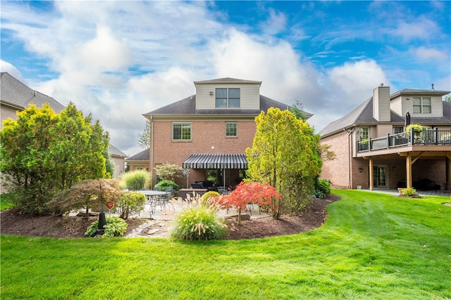 back of property featuring a lawn, a deck, and a patio area