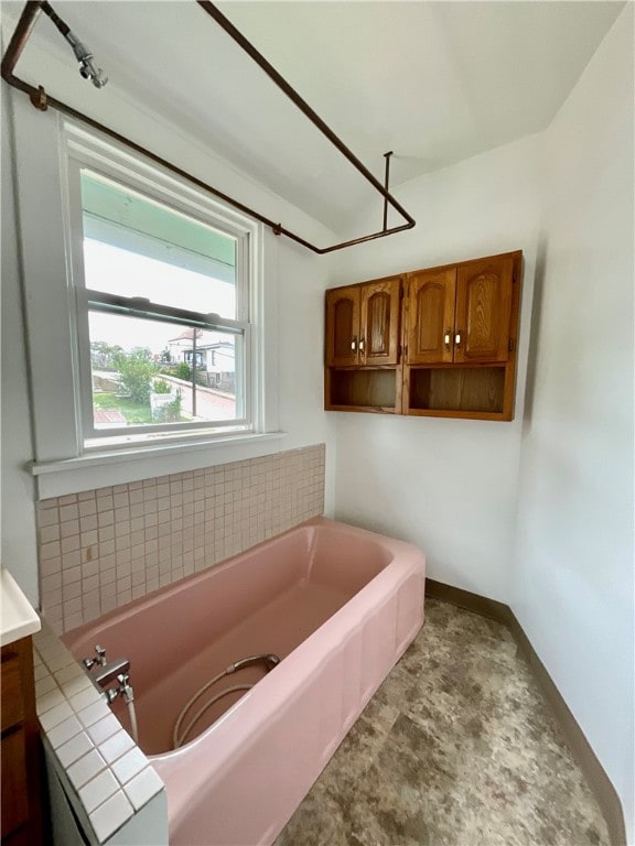 bathroom featuring backsplash, vanity, and a bath