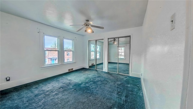 spare room featuring dark carpet and ceiling fan