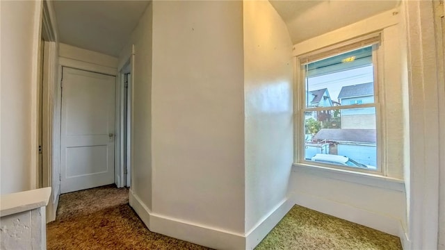 corridor featuring dark colored carpet