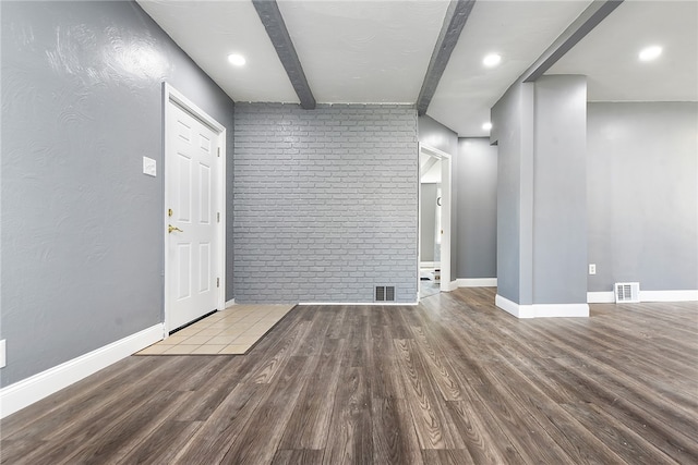 spare room featuring brick wall, beamed ceiling, and hardwood / wood-style flooring