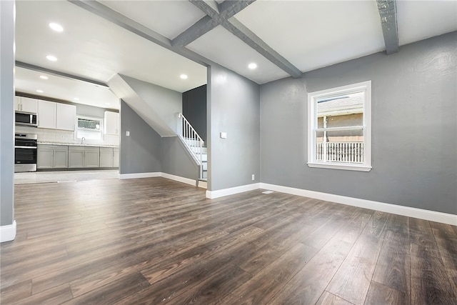 unfurnished living room featuring beamed ceiling, hardwood / wood-style floors, and sink