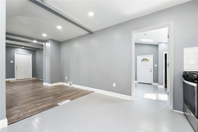 empty room with light hardwood / wood-style floors and beamed ceiling