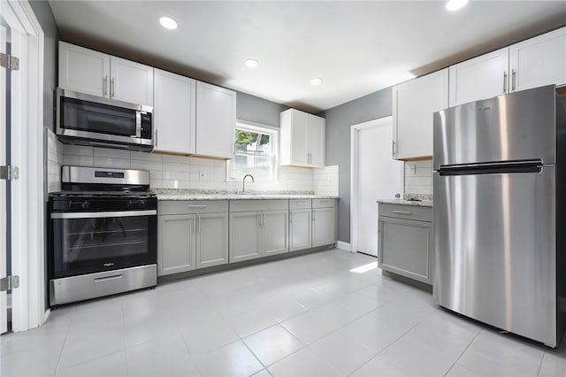 kitchen featuring gray cabinets, white cabinetry, appliances with stainless steel finishes, and sink