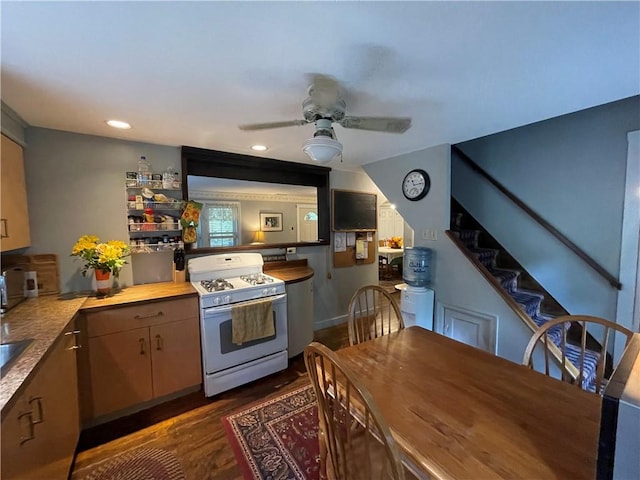 kitchen with white range with gas cooktop, ceiling fan, kitchen peninsula, and dark wood-type flooring