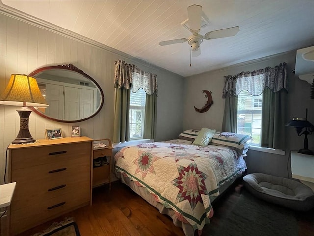 bedroom with dark hardwood / wood-style floors, ceiling fan, and wooden walls