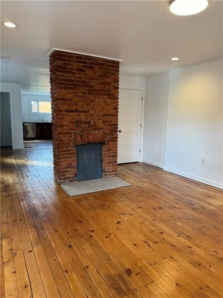 unfurnished living room featuring a brick fireplace and hardwood / wood-style floors