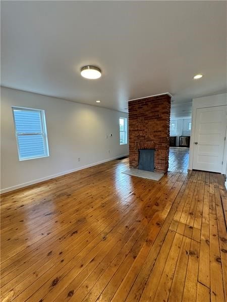 unfurnished living room with a large fireplace and light wood-type flooring