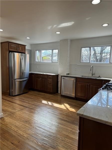 kitchen featuring appliances with stainless steel finishes, light wood-type flooring, sink, and a wealth of natural light