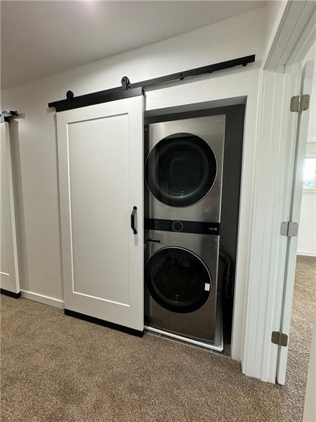 washroom with carpet, a barn door, and stacked washer and clothes dryer