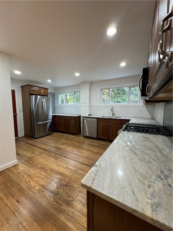 kitchen with sink, stainless steel appliances, light stone countertops, dark hardwood / wood-style flooring, and decorative backsplash