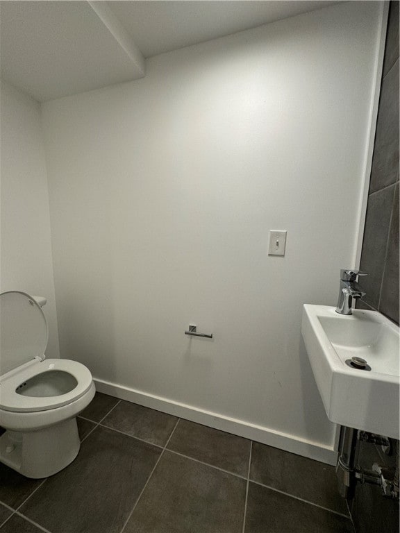 bathroom with toilet, sink, and tile patterned floors