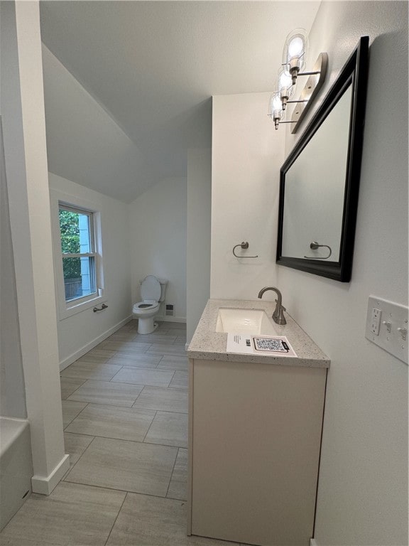 bathroom with lofted ceiling, vanity, and toilet