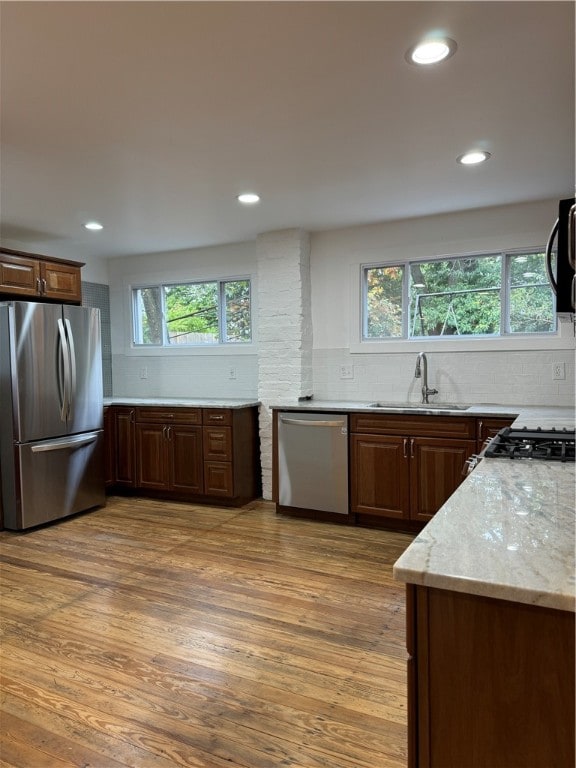 kitchen with stainless steel appliances, light hardwood / wood-style floors, a healthy amount of sunlight, and sink