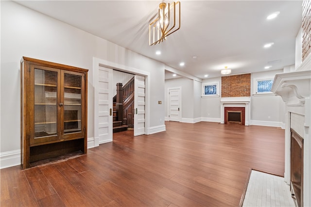 unfurnished living room featuring a notable chandelier and dark hardwood / wood-style floors