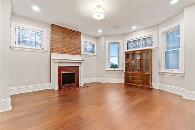 unfurnished living room featuring a brick fireplace and wood-type flooring