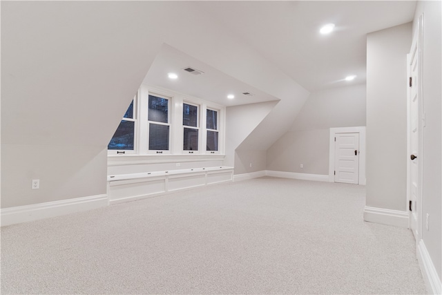 bonus room with lofted ceiling and light carpet