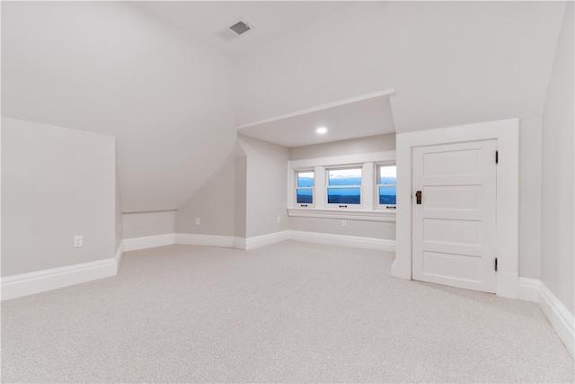 additional living space featuring lofted ceiling and light colored carpet