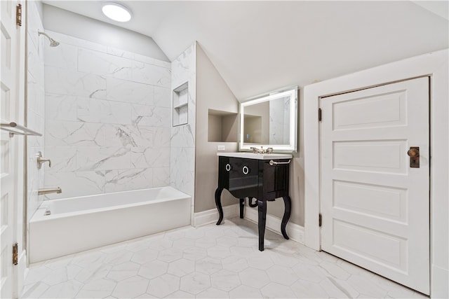 bathroom with vanity, vaulted ceiling, and tiled shower / bath