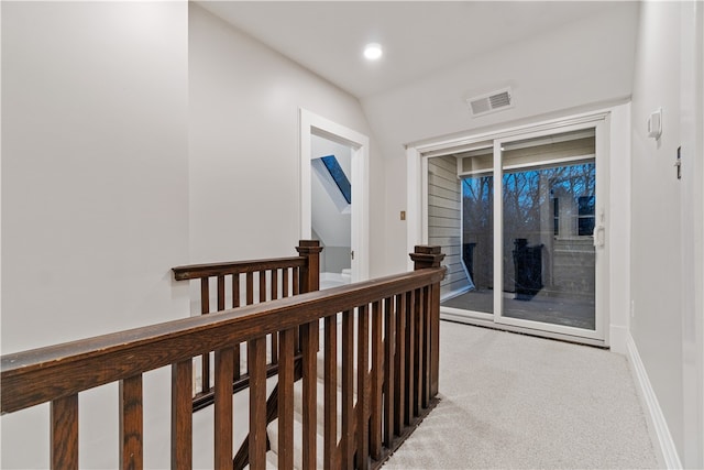 corridor with vaulted ceiling and light colored carpet