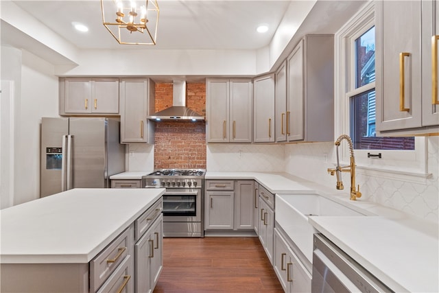 kitchen featuring backsplash, dark wood-type flooring, wall chimney range hood, stainless steel appliances, and a notable chandelier