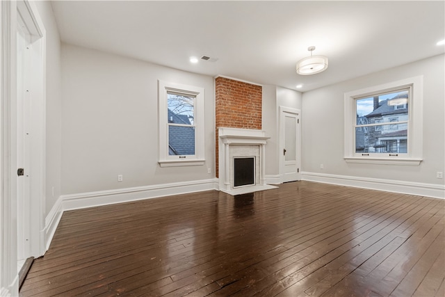 unfurnished living room featuring a brick fireplace and dark hardwood / wood-style floors