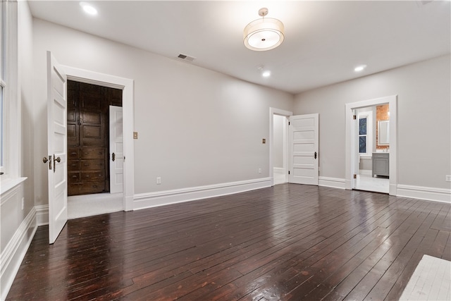 unfurnished bedroom with connected bathroom and dark wood-type flooring