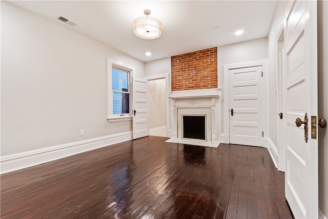 unfurnished living room with dark hardwood / wood-style flooring and a brick fireplace