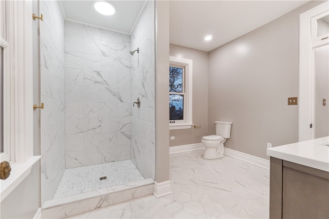 bathroom with a tile shower, vanity, and toilet