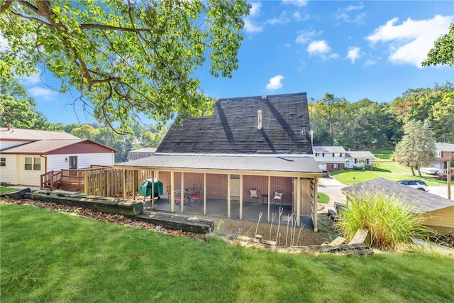 rear view of property with a deck, a yard, and a patio area