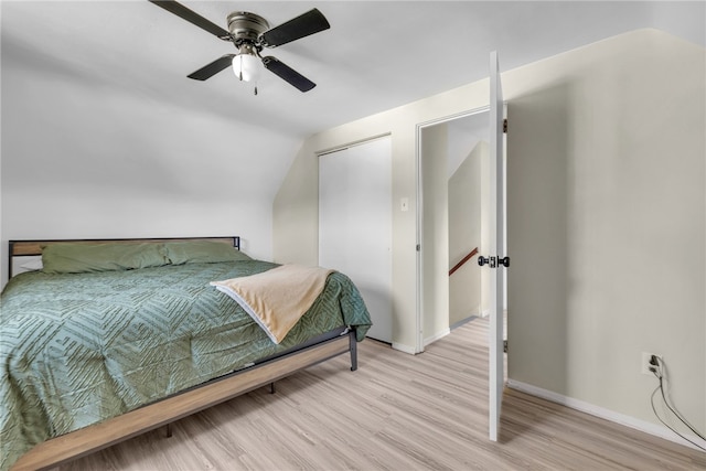 bedroom with a closet, light wood-type flooring, vaulted ceiling, and ceiling fan