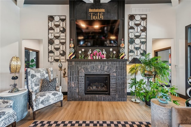 living room featuring wood-type flooring and a tiled fireplace