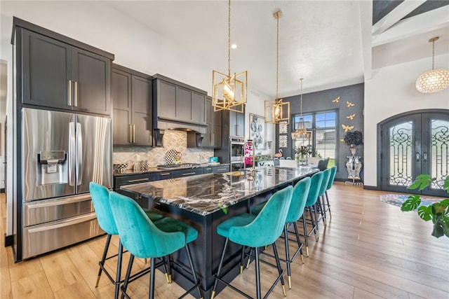 kitchen with a breakfast bar area, a kitchen island with sink, stainless steel appliances, and light hardwood / wood-style flooring