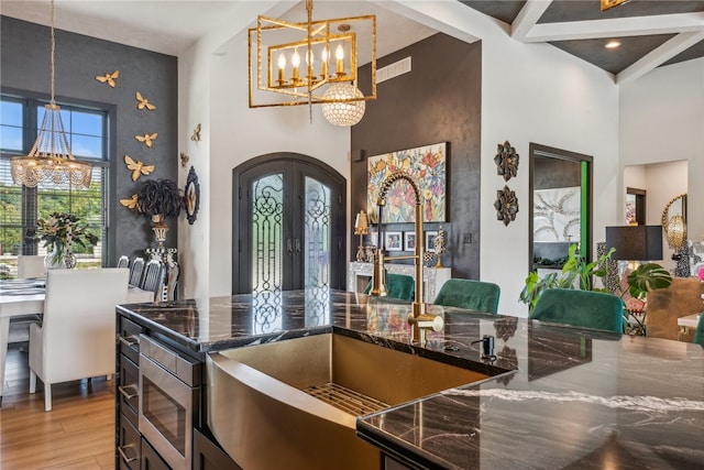 kitchen featuring a towering ceiling, pendant lighting, light hardwood / wood-style flooring, french doors, and sink