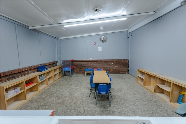 rec room with brick wall and light colored carpet