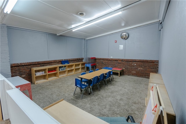 game room with light colored carpet and brick wall