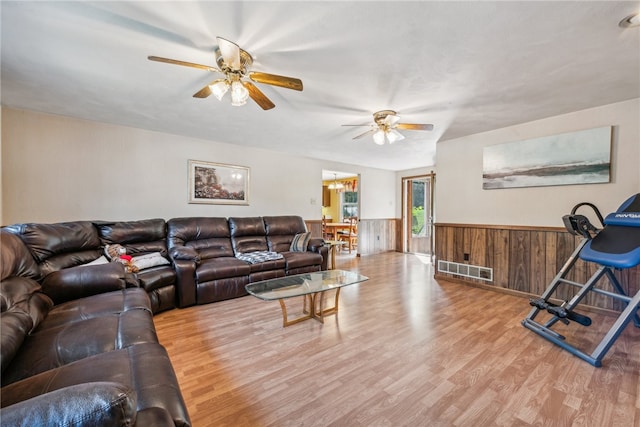 living room with ceiling fan, hardwood / wood-style flooring, and wooden walls