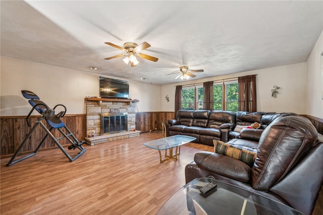 living room featuring ceiling fan, hardwood / wood-style flooring, a fireplace, and wood walls